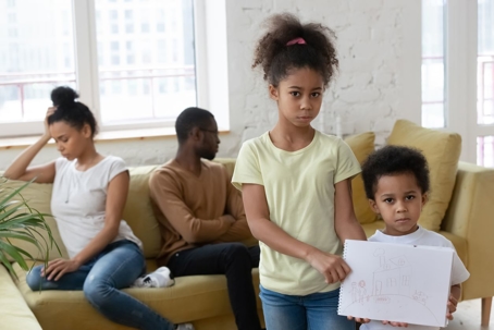 two children in front of parents disagreeing on couch