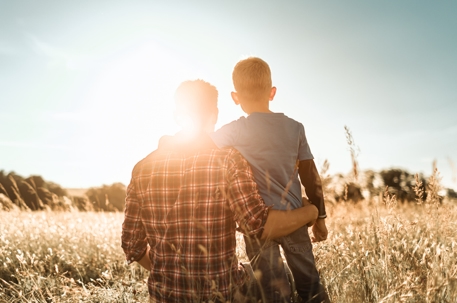 father and son hugging in a field