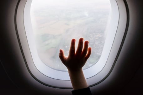 Child's hand on plane window