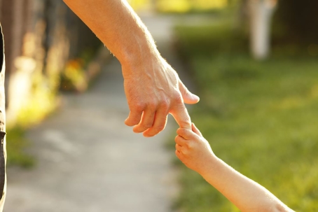 older parent holding hands with young child