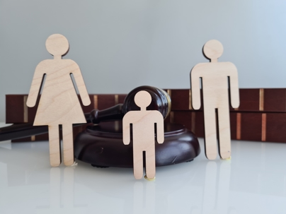 Wooden Figures Representing a Family Near a Gavel and Law Books