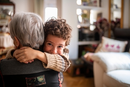 Grandchild is giving a warm hug to grandmother, expressing love and affection in a cozy home environment